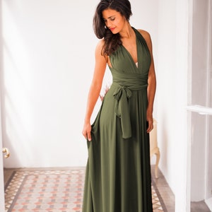 A woman wearing a deep-v neck olive long dress in a beautiful light.
