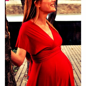 May include: A woman in a red wrap dress with a deep V-neckline. The dress has a sash that ties at the waist.
