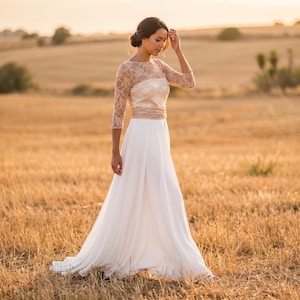 Peut inclure: Une robe longue au sol dotée d'une jupe blanche fluide et d'un corsage ajusté avec des manches en dentelle trois-quarts. Le corsage est confectionné dans une dentelle fine et transparente qui recouvre les épaules et les bras, créant une silhouette raffinée.