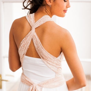 Close-up of a model wearing a bridal gown. This combines a long skirt, a tulle overskirt, a tube top, and convertible straps in pink lace. The straps are crossed on her back but this is not the only way to wear it, as it's a convertible dress