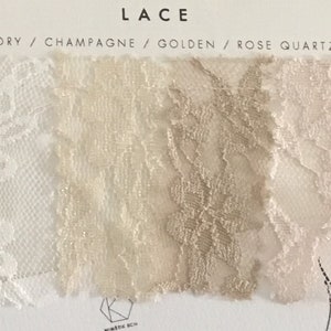 May include: A fabric swatch card labeled LACE with four color options: Ivory, Champagne, Golden, and Rose Quartz. Each section displays a distinct floral lace pattern in its respective color, arranged horizontally on a white background.