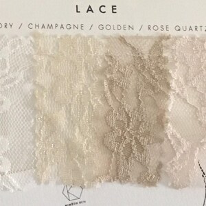 May include: A fabric swatch card labeled LACE with four color samples: Ivory, Champagne, Golden, and Rose Quartz. Each section displays a distinct floral lace pattern in its respective hue, arranged horizontally on a white background.