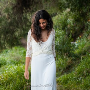 The model is wearing the same simple wedding dress with an elegant ivory lace bolero. The bolero is convertible, so it can be worn in different ways. She has wrapped it with deep v-neck.