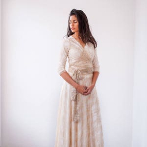 Lovely woman staring in a room wearing a bridal gown in golden lace with 3/4 sleeves