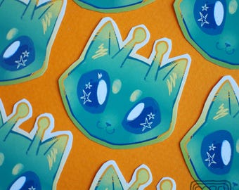 May include: A collection of stickers featuring a teal cat-like alien design with large blue eyes and star accents. The stickers have yellow antennae and are set against an orange background. The stickers are cut out with a white border.