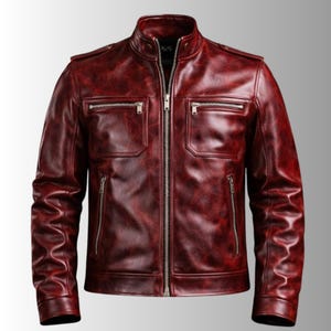 May include: A burgundy leather jacket with a stand-up collar and a zip-up front. The jacket has two chest pockets and two side pockets, all with zippers. The sleeves are long and have a classic design. The jacket is a solid color and has a slightly distressed look.