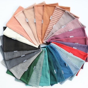 May include: A collection of 20 colourful fabric headbands arranged in a circle. The headbands are made of a soft, stretchy material and feature a variety of colours and patterns, including solid colours, stripes, and polka dots.