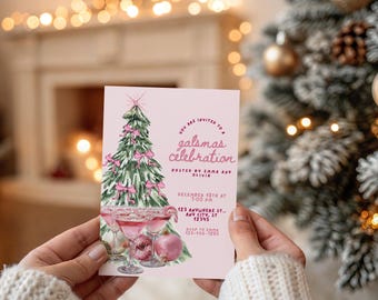 May include: A pink invitation card with the text "galsmas celebration" and a watercolor illustration of a Christmas tree decorated with pink bows. The card also features images of cocktails and apples. The invitation is held in front of a Christmas tree.