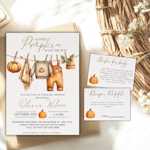 May include: Baby shower invitation set with a pumpkin theme. The invitation features watercolor illustrations of baby clothes, a pumpkin, and the text "A Little Pumpkin is on the Way." Includes inserts for books and diapers.