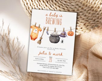 May include: A baby shower invitation with a Halloween theme. The invitation features a clothesline with a baby onesie, a witch's hat, a cauldron, and a pumpkin. The text reads "a baby is brewing". The invitation is for Julia & Mark.