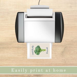 K&ouml;nnte beinhalten: Ein wei&szlig;er Drucker mit einer schwarzen Seitenwand druckt eine Karte mit einer Aquarell-Illustration eines gr&uuml;nen Brokkolis und dem Text "week thirty broccoli".