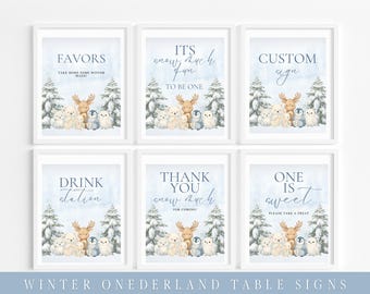 May include: Six framed winter-themed signs with watercolor illustrations of woodland animals and text. The signs read "Favors," "It's snow much fun," "Custom sign," "Drink station," "Thank you," and "One is sweet."