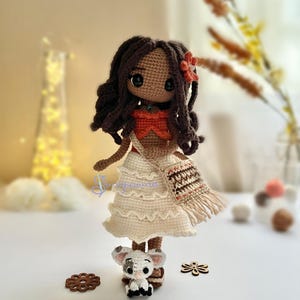 May include: A crocheted doll with brown hair, a white dress, and a brown and orange bag. The doll is holding a small crocheted pig.