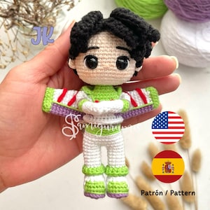 Puede incluir: Juguete amigurumi de crochet de un personaje que lleva un atuendo verde, blanco y rojo con un chaleco morado. El juguete tiene cabello negro y ojos marrones. El fondo incluye una bandera de Estados Unidos y una bandera de España. El texto "Patrón / Pattern" es visible en la imagen.