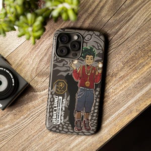 May include: A phone case with a cartoon illustration of a character with green hair, wearing a red shirt and blue shorts. The case has a gray and black patterned background and the text "JAKE LONG THE AMERICAN DRAGON SHEVA STELLA".