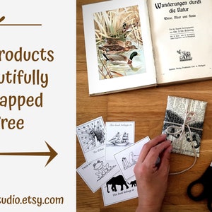 Puede incluir: Un primer plano de un regalo envuelto en papel marr&oacute;n con cuerda y una etiqueta. El regalo est&aacute; rodeado de otros materiales de envoltura de regalos, incluyendo un libro, tijeras, cuerda y una bola de hilo. El texto "Wanderungen durch die Natur" es visible en el libro. El texto "All our products are beautifully gift wrapped for free" es visible en el lado izquierdo de la imagen.