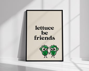 May include: A framed art print with the text "lettuce be friends" in black. Two cartoon lettuce characters with large eyes and holding hands are below the text. The background is a light beige color.
