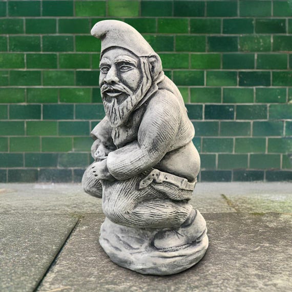 A hand-cast concrete gnome caught mid-sit on a tiny toilet — the kind of yard art that makes neighbors do a double-take and guests lose it.