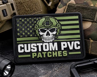 May include: A rectangular PVC patch featuring a stylized American flag design in black and olive green. Centered on the flag is a white skull wearing an olive green tactical helmet. The text CUSTOM PVC PATCHES is printed in white below the skull.