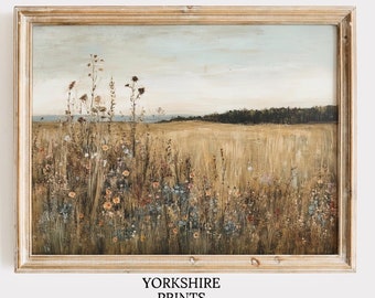 May include: A framed painting depicting a field of wildflowers with a forest in the background. The painting is in a light wood frame and has a rustic, vintage feel.
