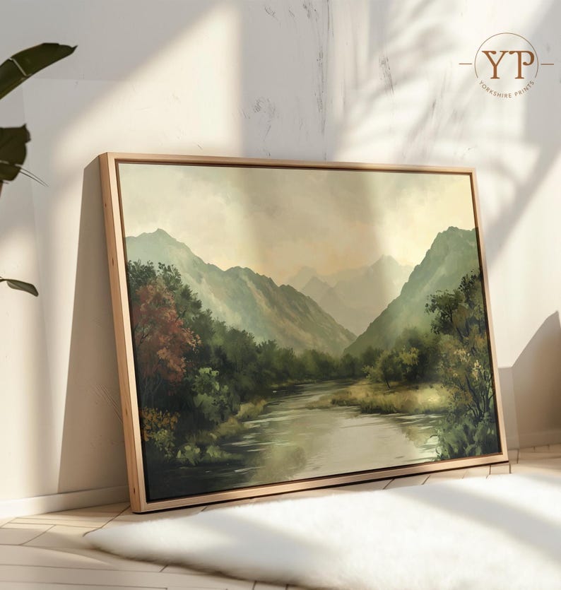 May include: A framed landscape painting depicting a river winding through a valley with lush green trees and mountains in the background. The sky is a soft, muted blue with hints of pink and orange.