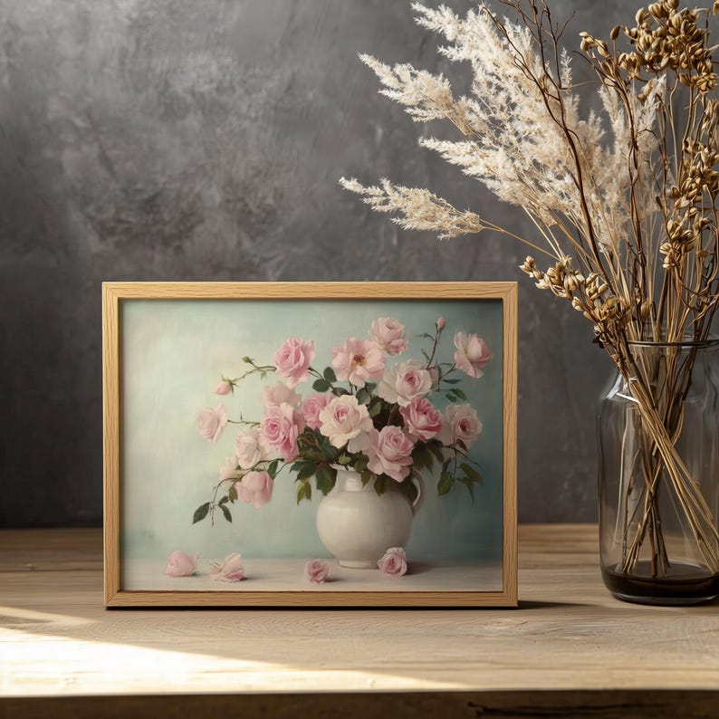 May include: A framed painting of a bouquet of pink roses in a white vase. The roses are arranged in a loose, natural style, and the vase is simple and elegant. The background is a soft blue-green color.