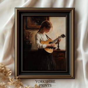 May include: A framed painting depicting a young person playing a guitar in a dimly lit room. The person is wearing a white blouse and a dark skirt. The guitar is brown with a light wood finish. The painting is set in a black frame with a gold trim.