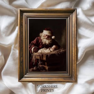 May include: Framed print featuring Santa Claus gazing at a baby in a manger. Santa is dressed in a red suit with a white beard and hat. The print has a gold-colored frame. The text "YORKSHIRE PRINTS" is at the bottom.
