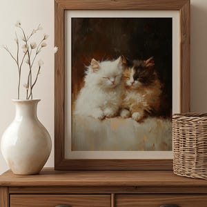 May include: A framed painting of two white and brown kittens cuddling together. The kittens are sleeping with their eyes closed. The painting is set against a dark brown background.
