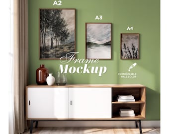 Könnte beinhalten: Drei rechteckige Wandrahmen mit der Beschriftung A2, A3 und A4, die Landschaftskunst zeigen. Die Rahmen sind über einem Holz-Sideboard mit weißen Schiebetüren und offenen Regalen montiert. Text: Frame Mockup und Customizable Wall Color.