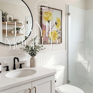 Puede incluir: Interior de baño con mueble de lavabo blanco, grifo negro y espejo redondo. Una impresión floral enmarcada cuelga de la pared. El texto "FRAME MOCKUP" está superpuesto.