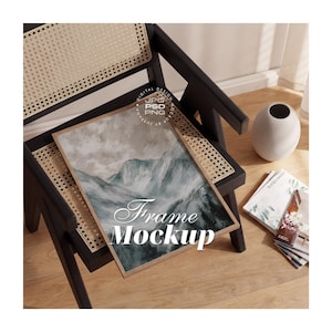 Puede incluir: Un marco de fotos rectangular de madera sobre una silla negra con asiento de rejilla. El marco muestra una pintura de paisaje de montaña abstracto en tonos azules, grises y blancos. El texto Frame Mockup está impreso en color blanco.