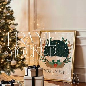 Puede incluir: Una maqueta con temática navideña que presenta un árbol decorado, obras de arte enmarcadas y cajas de regalo envueltas. La obra de arte muestra un diseño de globo de nieve con las palabras "NOEL & JOY". El marco es dorado y las cajas de regalo son de color crema con cintas negras.