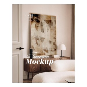 Puede incluir: Una maqueta de marco de pared rectangular vertical con una pintura abstracta en tonos marrón, beige y blanco. El marco es delgado y metálico. Las superposiciones de texto incluyen JPG, PSD, PNG y las palabras Frame Mockup en letra blanca.