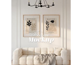 May include: Two rectangular wall art prints in light wood frames featuring Matisse-inspired abstract botanical and figure illustrations in black and beige. The prints are displayed above a cream-coloured tufted sofa with a textured throw blanket.
