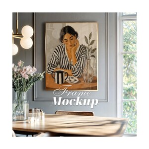 Puede incluir: Una lámina de arte mural rectangular en un marco dorado fino con la ilustración de una persona con camisa de rayas blancas y negras sentada a una mesa con una taza a rayas, una taza pequeña y un jarrón con ramas. El texto Frame Mockup es visible.
