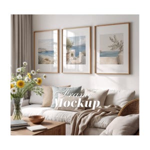 Puede incluir: Tres marcos de pared rectangulares verticales con bordes de madera clara, cada uno con una impresión de paisaje costero con mar azul, edificios blancos y ramas de olivo. El texto Frame Mockup está superpuesto en blanco.