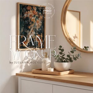 Puede incluir: Una impresión floral enmarcada con flores naranjas y amarillas cuelga de una pared blanca. Un espejo redondo y una bandeja de madera con una vela, un dispensador de jabón y una pequeña planta en un cuenco blanco se encuentran sobre un mueble de madera. Se muestra el texto "FRAME MOCKUP".