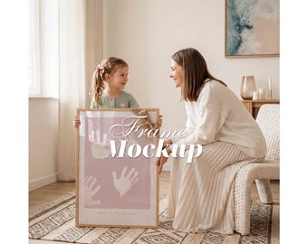 Puede incluir: Un marco de fotos rectangular de madera con fondo rosa claro, huellas de manos blancas y el texto "Anne Julia, 8 jaar" en la parte inferior. El marco está decorado con un lazo de cinta color canela en la parte superior y muestra "Frame Mockup".