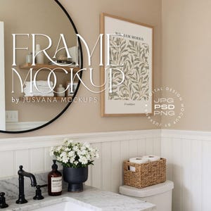 Puede incluir: Maqueta de baño con una impresión botánica enmarcada, un grifo negro y un jarrón azul oscuro con flores blancas. También se ven un espejo redondo negro y una cesta de mimbre con papel higiénico. El texto "FRAME MOCKUP" está superpuesto.