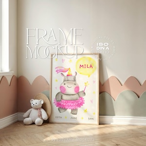 Puede incluir: Un cuadro enmarcado con una ilustración de acuarela de un hipopótamo con un gorro de fiesta y tutú, sosteniendo una varita mágica. La impresión incluye el nombre "MILA", la fecha y la hora. La escena es en una habitación infantil.