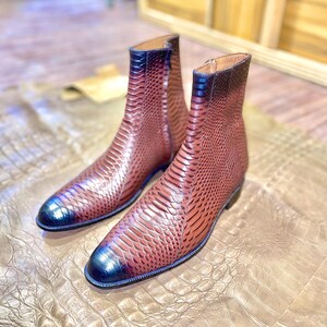 May include: A pair of brown leather ankle boots with a snakeskin pattern. The boots have a pointed toe and a zip on the inside of the ankle.