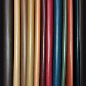 May include: A variety of leather strips in different colors, including brown, tan, red, blue, and green. The strips are arranged side by side, showing the different textures and shades of the leather.