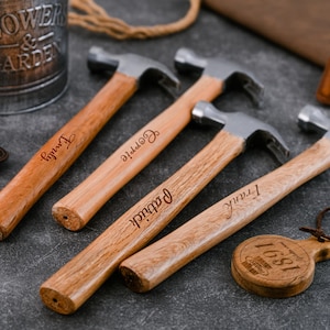 Puede incluir: Cuatro martillos con mangos de madera y cabezas plateadas, cada uno grabado con un nombre: Emily, Carrie, Patrick y Frank. También se ve una pequeña etiqueta de madera con el texto "1681" y una maceta de metal.