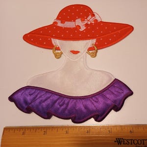 May include: An embroidered patch featuring a stylized woman wearing a red polka-dot hat with a white bow and gold hoop earrings. The woman has a purple off-the-shoulder top. The patch is on a white background.