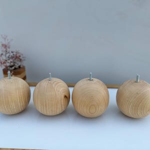 Op de afbeelding: Vier houten meubellepoten met een schroefdraad van metaal aan de bovenkant. De poten zijn rond en hebben een natuurlijke houtkleur.