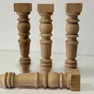 Puede incluir: Cuatro patas de mesa de madera sin terminar con un diseño torneado. Las patas miden aproximadamente 25 cm de alto y tienen una parte superior cuadrada.