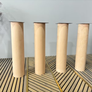 May include: Four wooden table legs with a dark gray top. The legs are light brown and have a smooth finish. The legs are arranged in a row on a wooden surface.