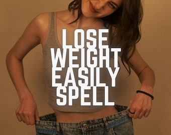 May include: A woman wearing a gray tank top and oversized blue jeans, holding the waistband open to show weight loss. The text "LOSE WEIGHT EASILY SPELL" is superimposed in white letters.