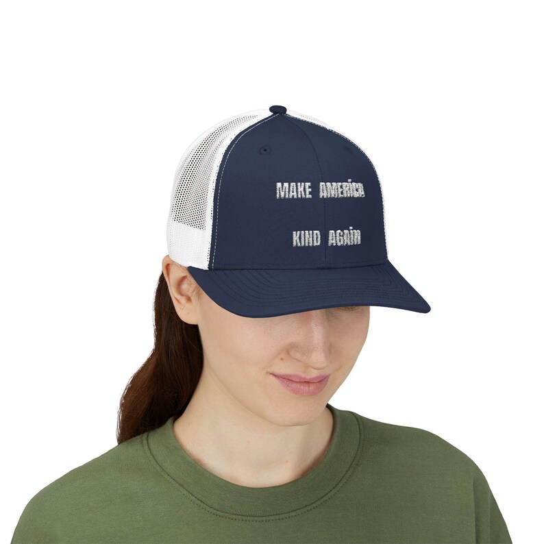 May include: A navy blue and white trucker hat with the text "Make America Kind Again" in white lettering.